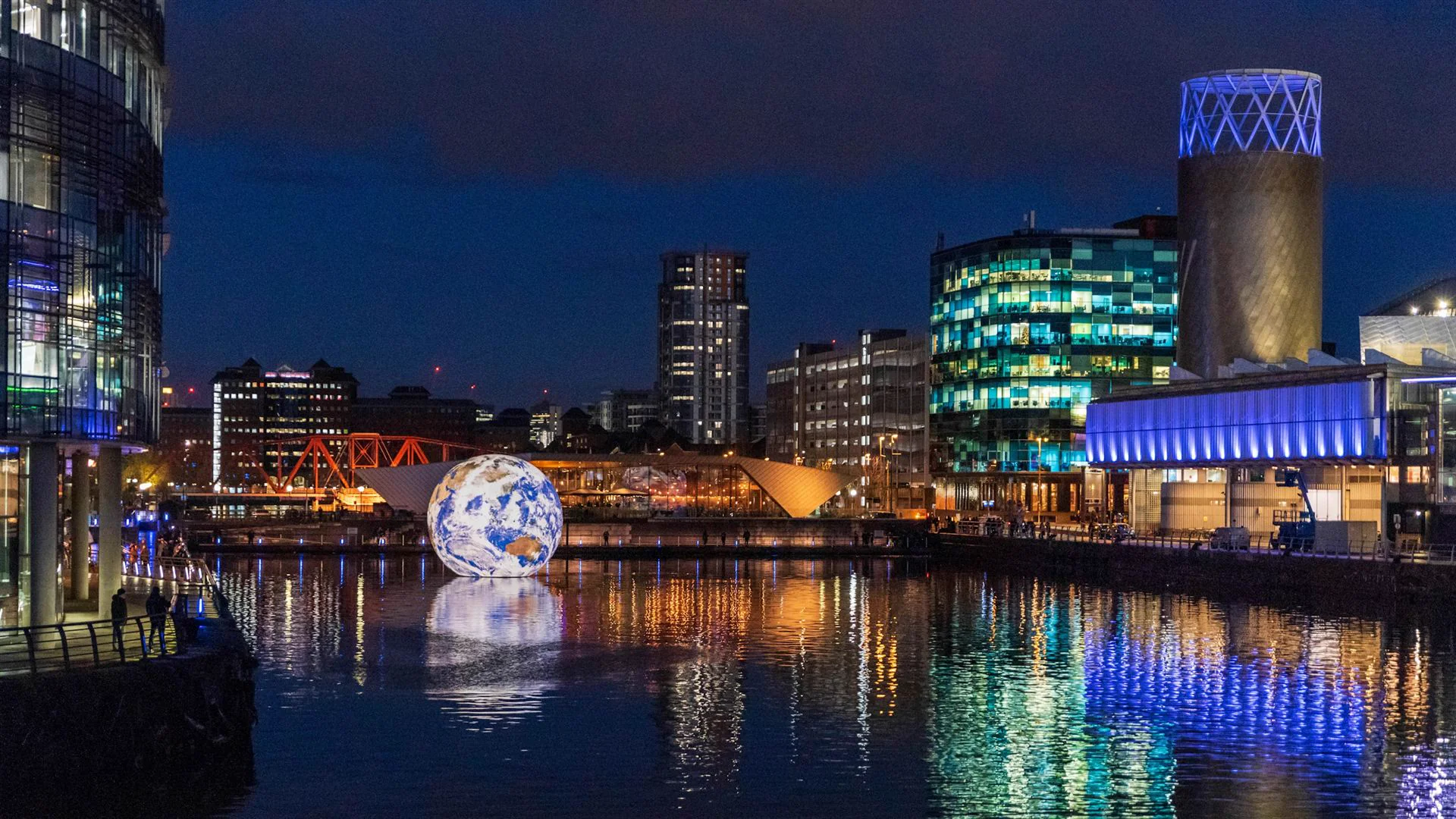 Salford Quays i Manchester på kvällen med upplysta byggnader som speglas i vattnet