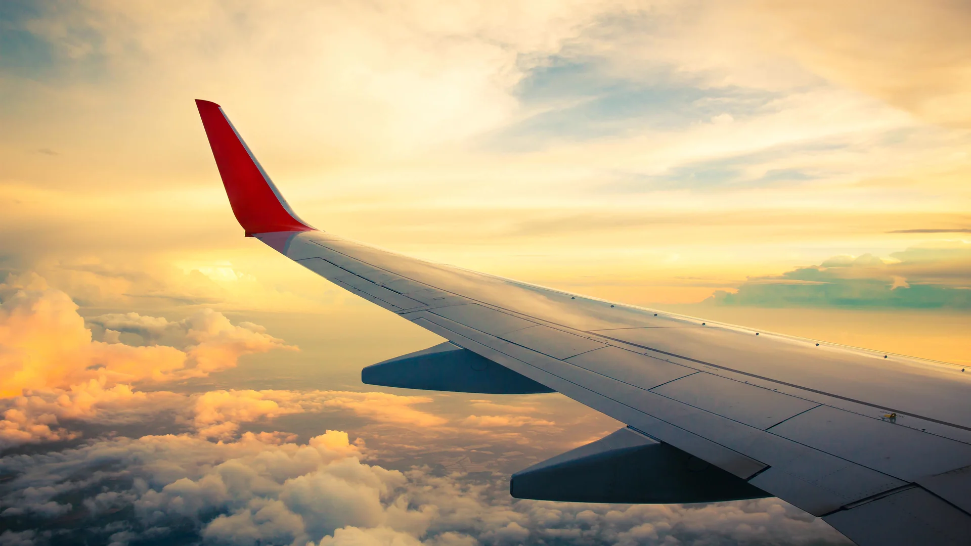 Flygplansvinge ovanför molnen i solnedgång
